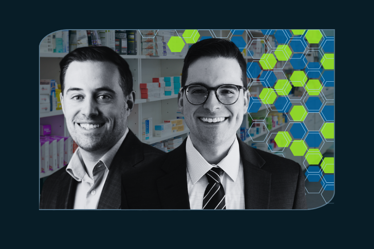 Two professionally dressed men in suits stand in front of pharmacy shelves, smiling confidently. The background includes a blue and green hexagonal digital overlay, symbolizing technology and data integration in the pharmaceutical or healthcare industry.